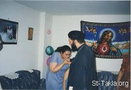 St-Takla.org Image: A new married woman kissing the hands of the Coptic Priest after the prayer of blessing new homes     :           