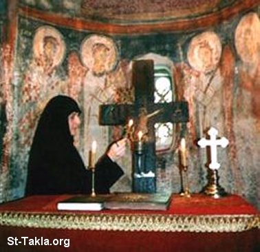 St-Takla.org Image: A nun lighting a candle at an ancient church صورة في موقع الأنبا تكلا: راهبة توقد شمعه في كنيسة أثرية